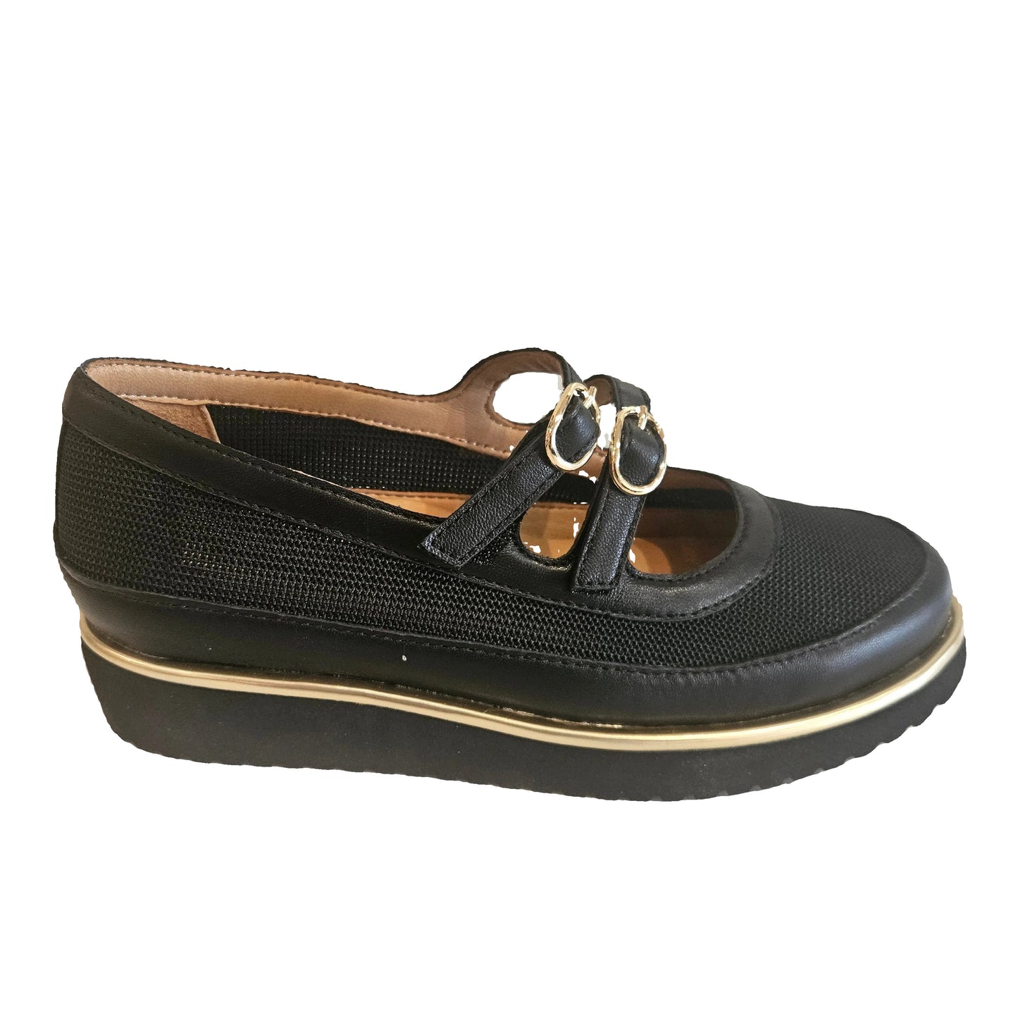 Black shoe with gold accents on a beige surface