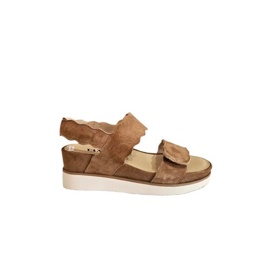 Brown sandal on a white surface with a neutral background
